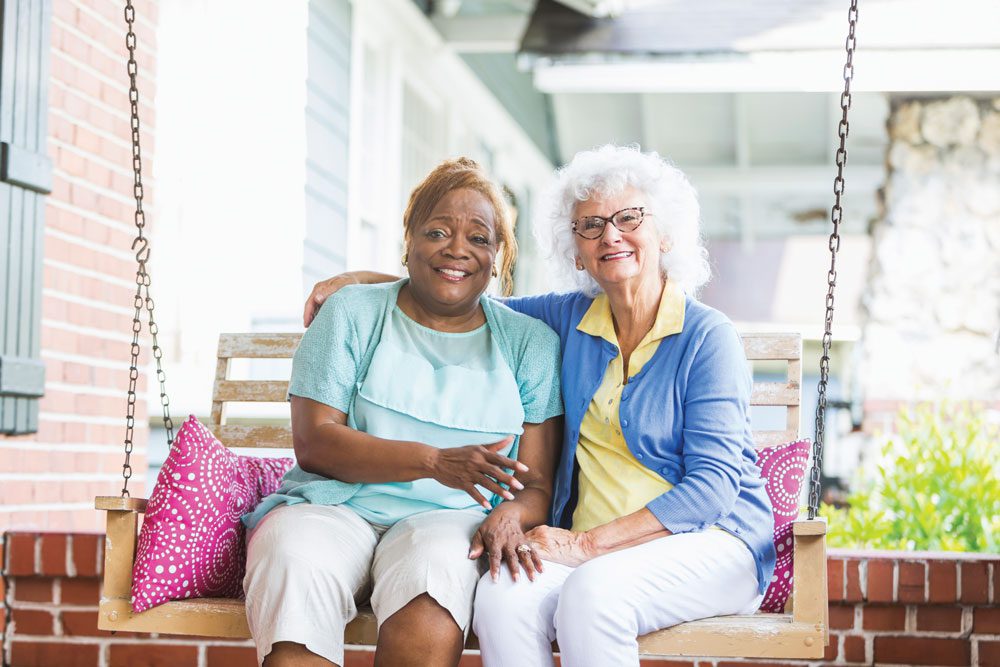 The Cottages of Fox Lake - Assisted Living and Memory Care Senior Living - two elderly women sitting on porch swing
