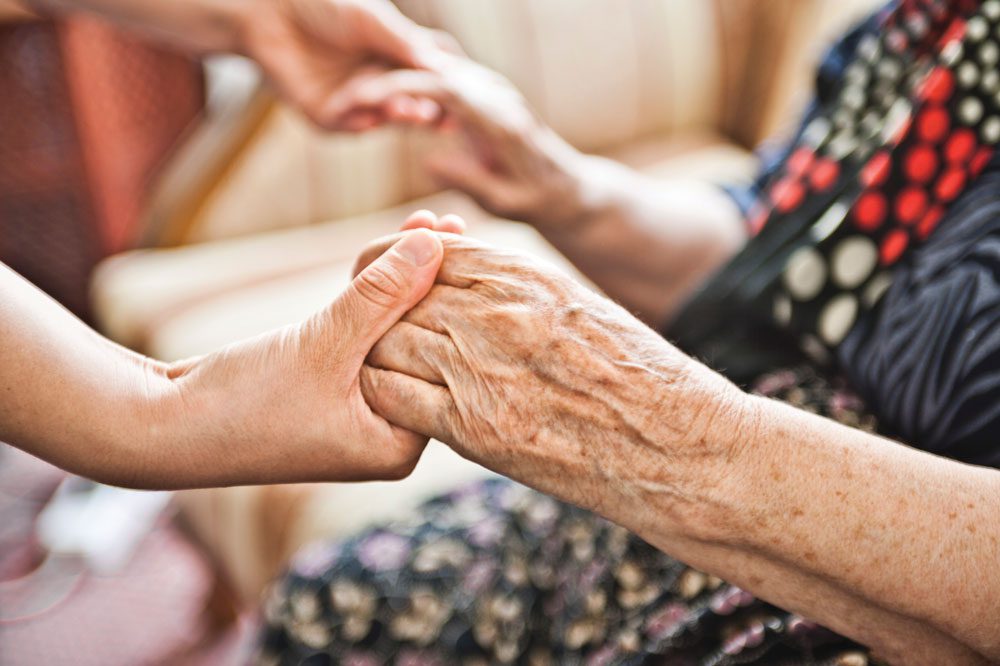 Cottages of Fox Lake - Memory care senior living resident grasping hands with young adult