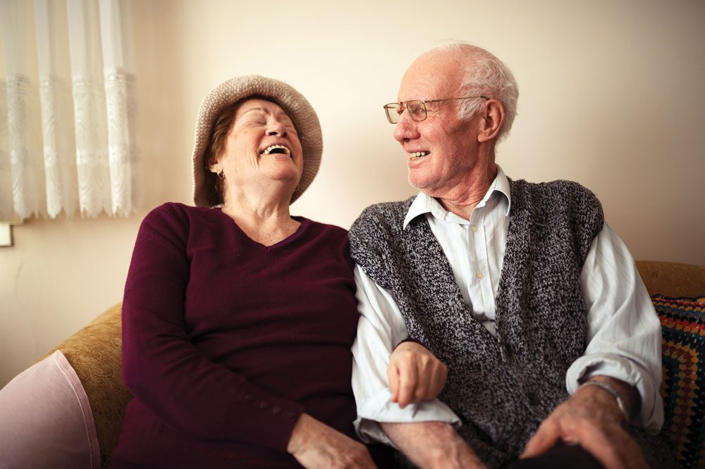 The Cottages of Fox Lake - Assisted Living and Memory Care Senior Living - married retirement community residents laughing on couch